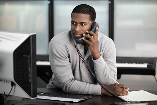 Black man using computer and talking on telephone